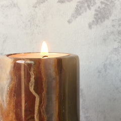 Solid Onyx stone candle in front of fern wallpaper