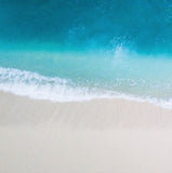 A light blue sea washing up on a sandy beach