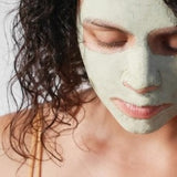 A woman wearing a green clay face mask