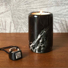 A black marble candle holder on a wooden worktop