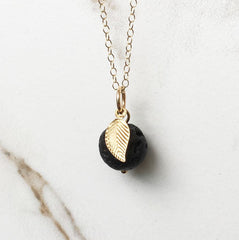 A necklace featuring a black lava ball and gold leaf