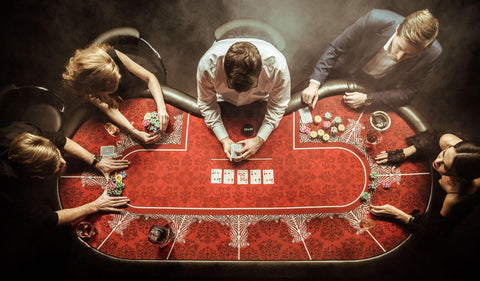 Five people playing Omaha poker at a red poker table. 
