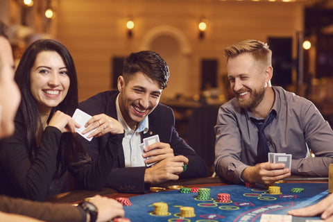 Three people smiling and playing poker at a blue poker table.
