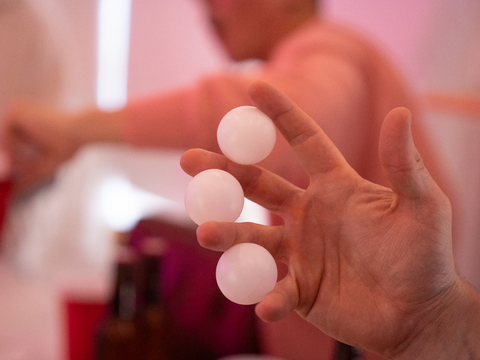 Three ping pong balls in between persons fingers.