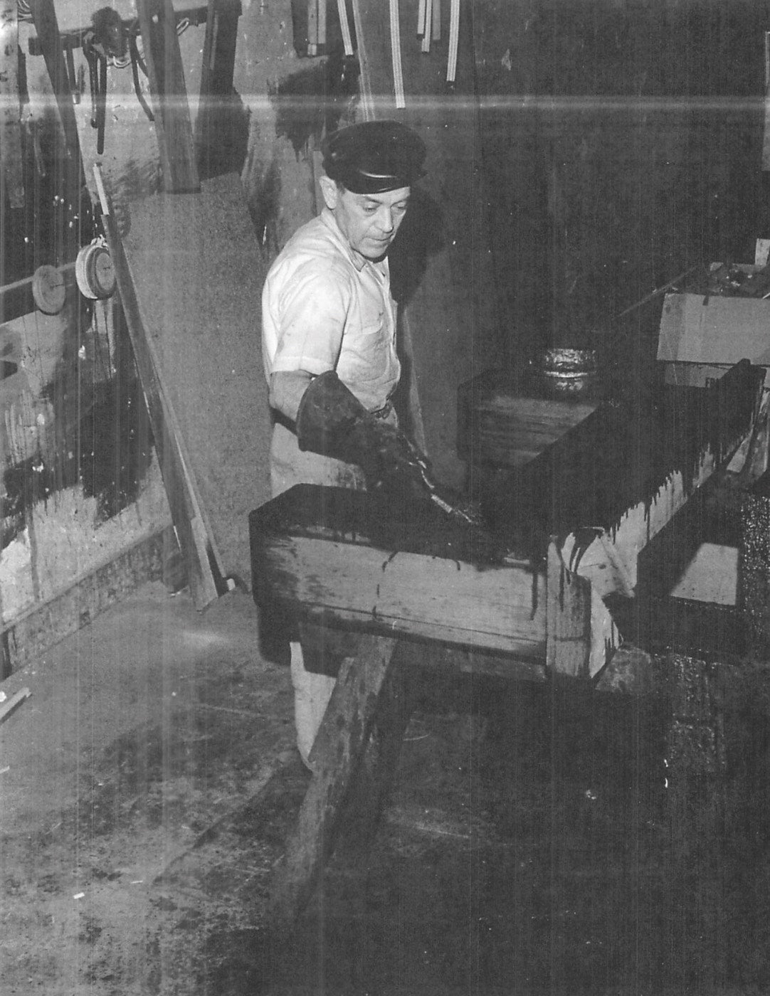 old black & white photo of man working on pool table