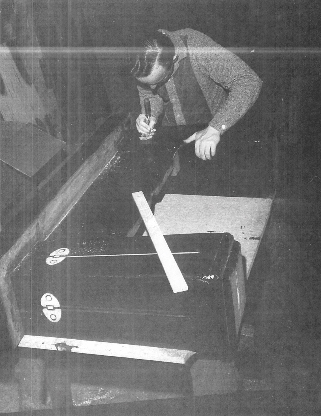 old black & white photo of man working on pool table