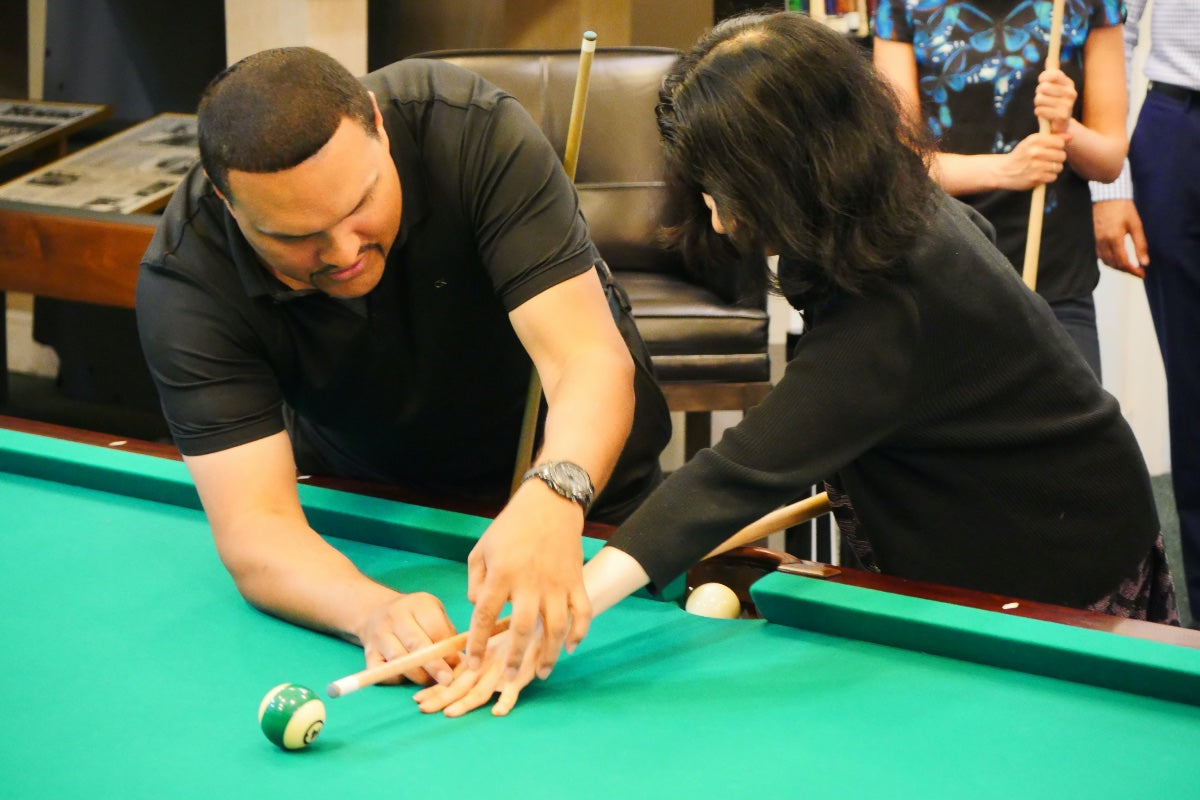 man teaching a woman billiards technique