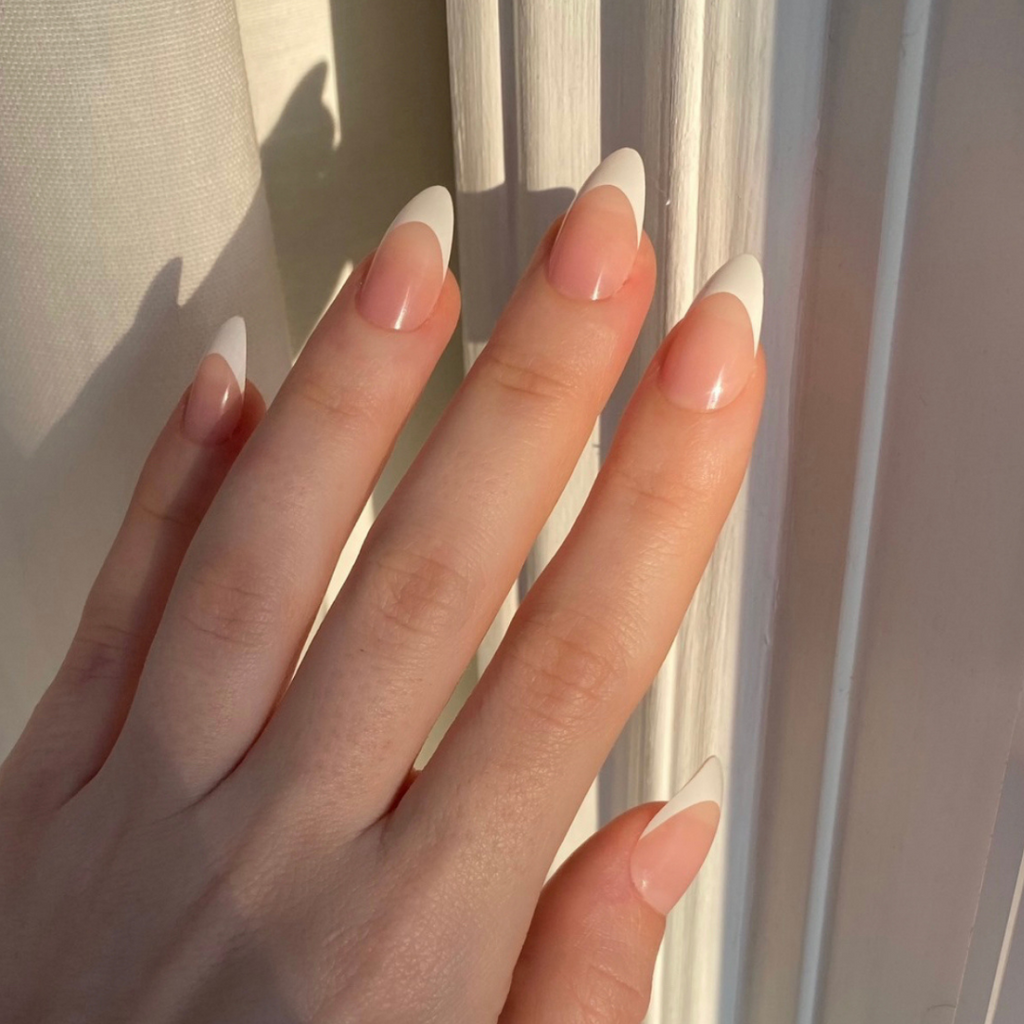 hand with almond shaped press on nails with french tip 