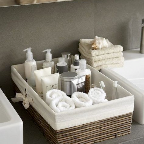 bathroom organizational basket with soaps, rolled face towels and skincare products