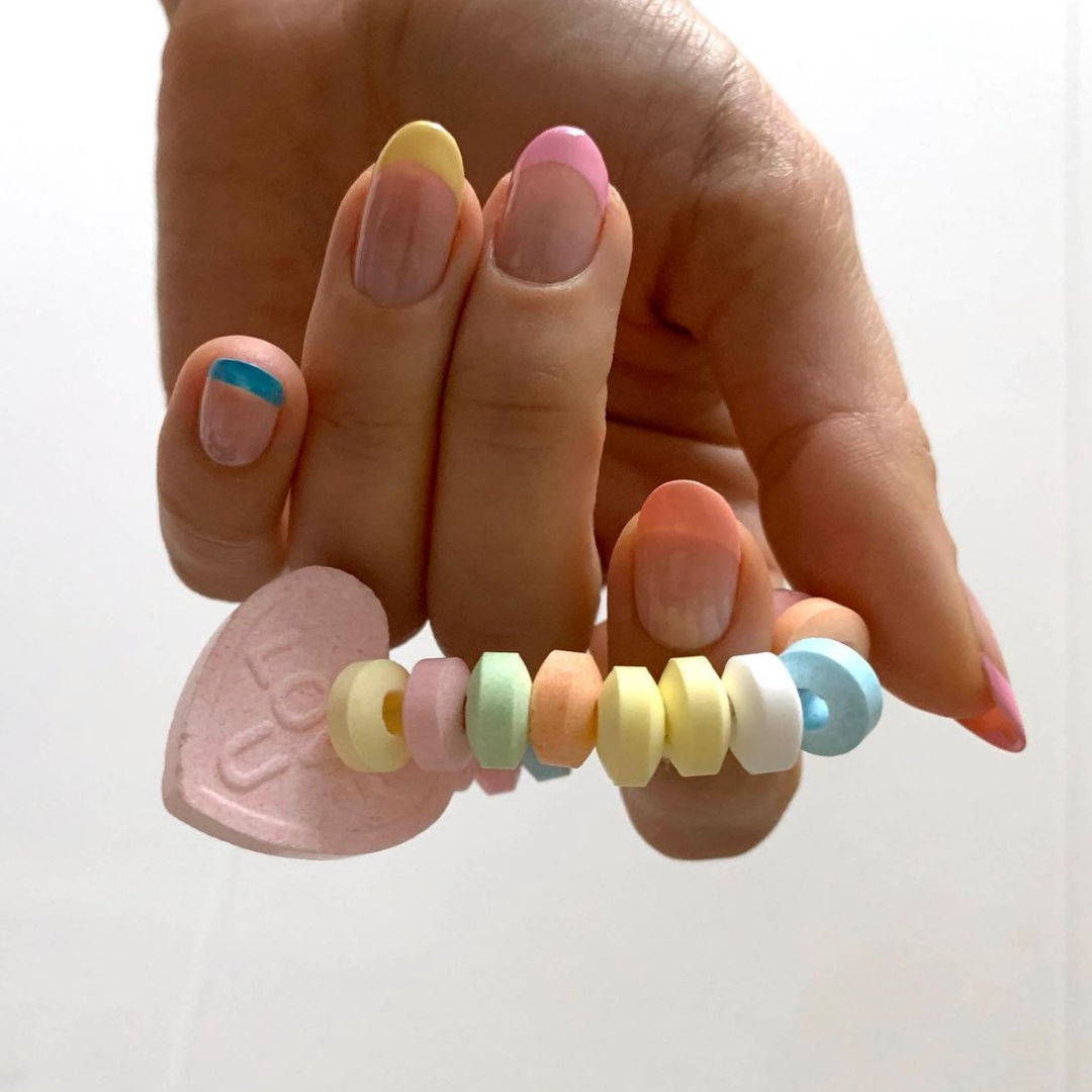 hand holding candy heart bracelet with french manicured nails in a variety of pastel colours