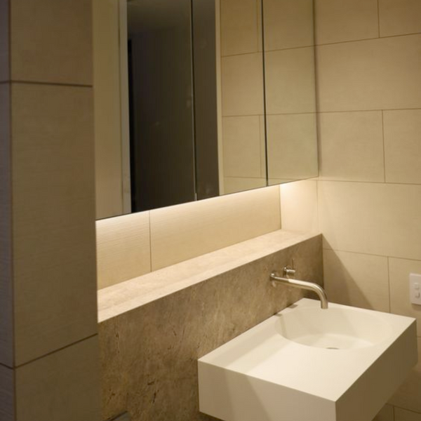 modern bathroom with dim lighting with white floating sink and large medicine cabinet mirror above