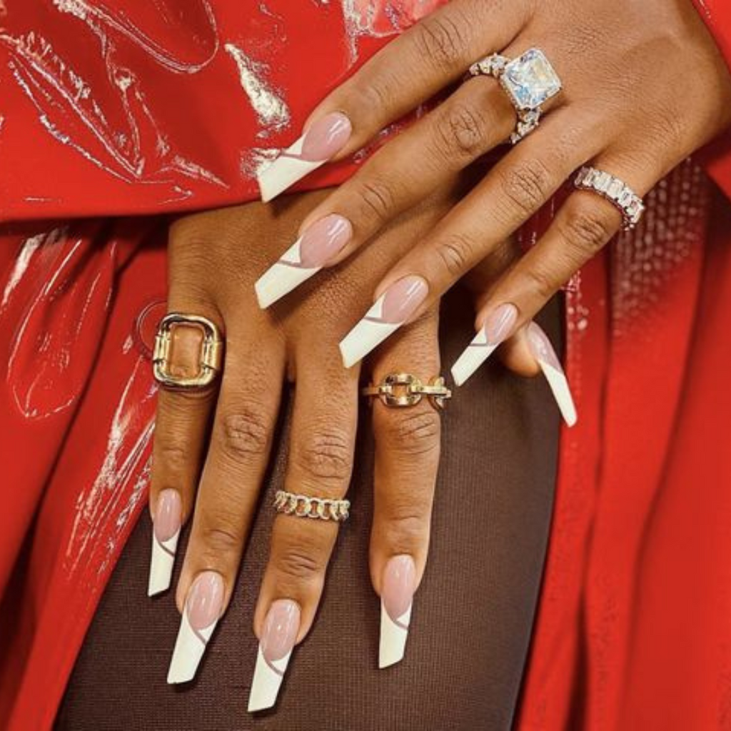 woman in red coat with hand wearing rings and long lipstick shaped nails