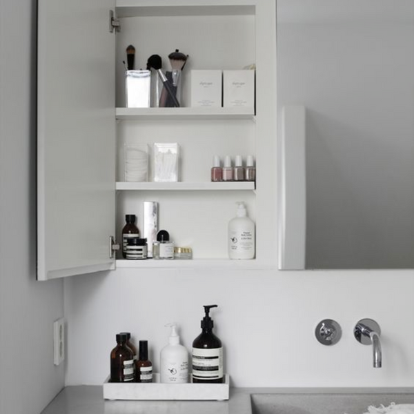 minimal medicine cabinet above sink opened with beauty products on shelves