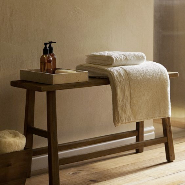 wooden stool with tray holding soap and towels folded 