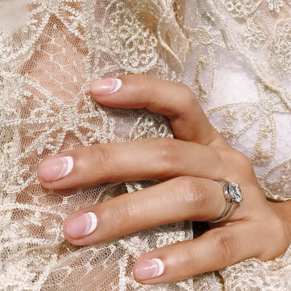 short natural nails with reverse french tip holding arm with lace sleeve