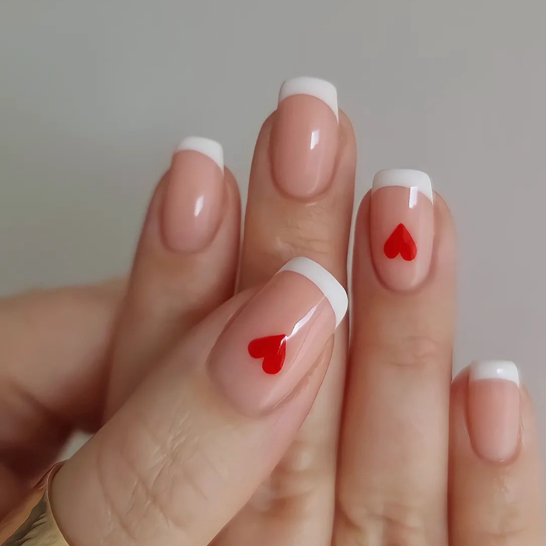 square french manicure nails with small red hearts on accent fingers