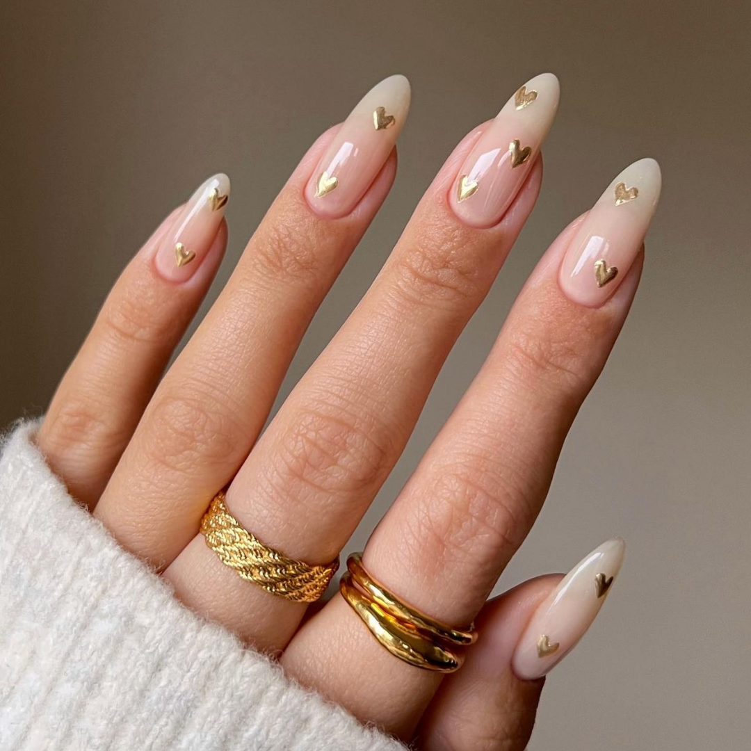 long nude almond shaped nails with small gold hearts