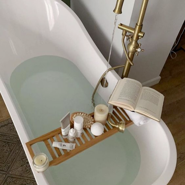 bathtub with bath tub tray holding open book and bath accessories