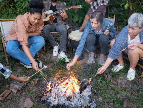 Family roasting marshmallows around a campfire while camping