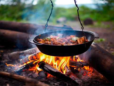 A pot of food cooking over a fire while fall camping