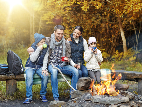 Happy Family sitting around a camp fire while camping in the fall