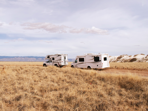 Two RVs in White Sands New Mexico with dune grass in the foreground and mountains in the background