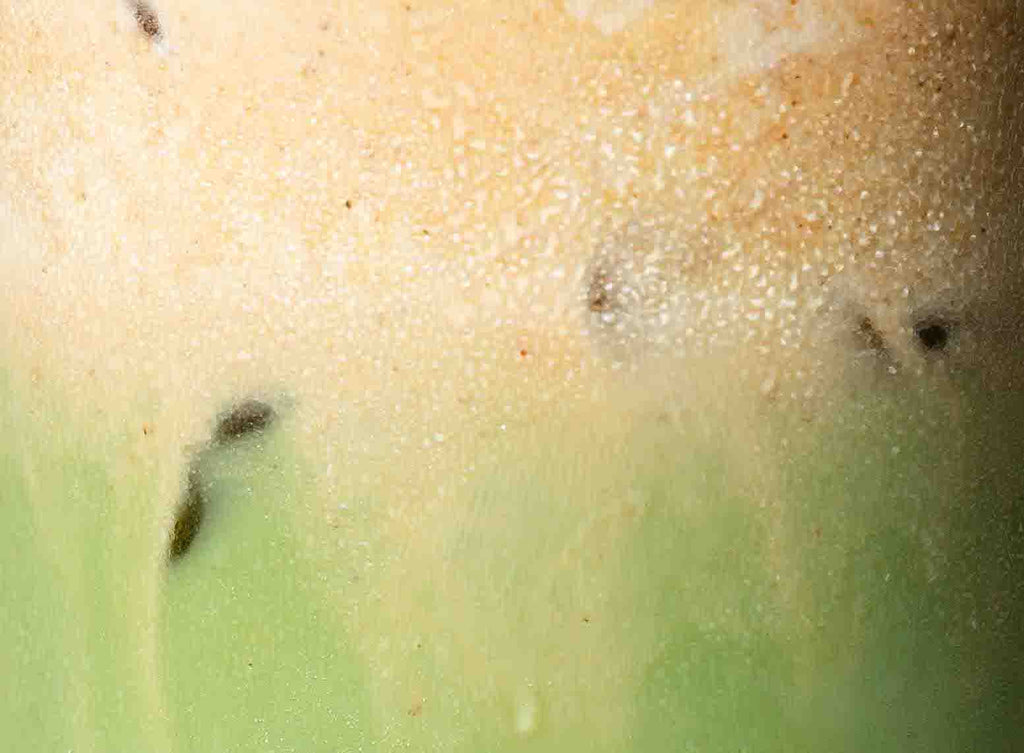 A close-up view of velvety pumpkin cold foam beautifully swirling on a glass of iced matcha, creating an enticing and seasonal beverage