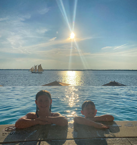 two young kids in an infinity pool with sunset behind them 