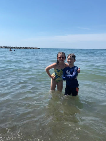 two young kids with arms around each other and smiling at camera while standing in Lake Erie at Presque Isle State Park 