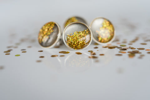 photo of charcoal resin with gold holographic glitter and clear resin in a silver plated bezel stud earrings casual earrings product photography 
