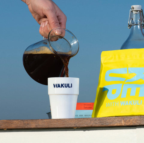 Zwarte koffie in een mok schenken met Wakuli zakje op de achtergrond - Verschil tussen Robusta en Arabica koffiebonen