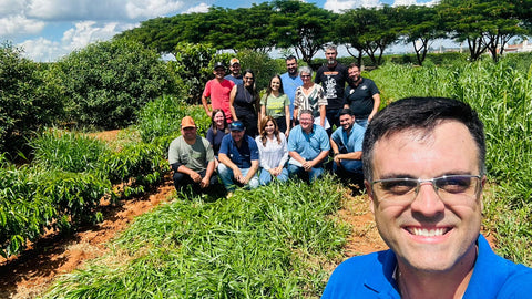 Regenerative agriculture - Man with glasses in foreground. 10 people standing behind him in a field with trees in the background.