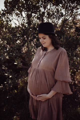 Pregnant women wearing a brown maternity dress that's breastfeeding friendly 