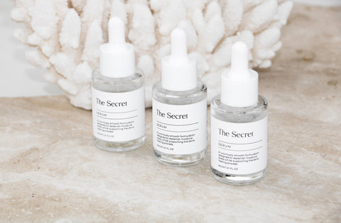 Three bottles of The Secret Skincare facial serums placed on a table.