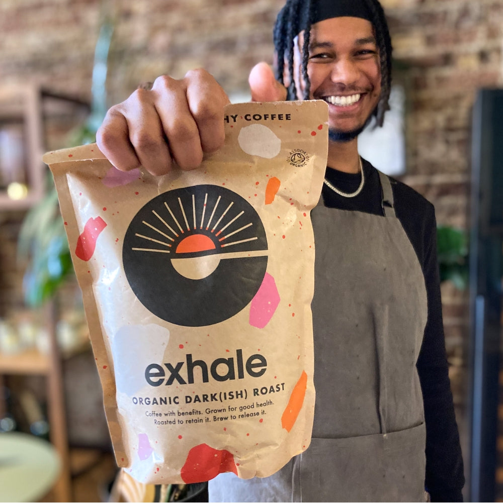 Exhale Healthy Coffee in a big bag being held by a handsome gentleman