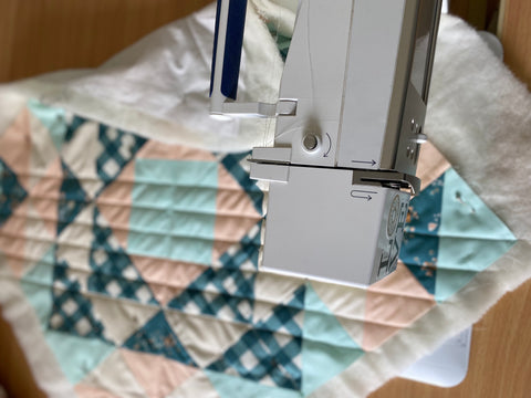 Pillow top under sewing machine.  Quilting lines visible