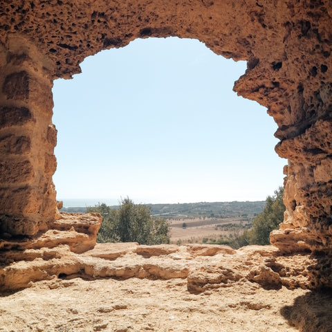 view of blue sky and landscape through ancient brick window