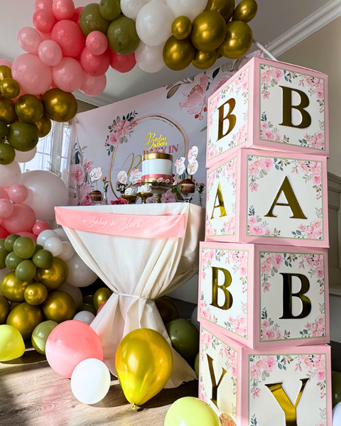 Floral Baby Shower Decoration set that contains the following:  Balloon Arch Garland Pink and Sage Green,  Baby Boxes with Letters, Oxford Cloth Backdrop, "Baby in Bloom" gold glitter cake topper and cupcake toppers, Satin Sash, FLOWER CONFETTI, Artificial Flowers Garland