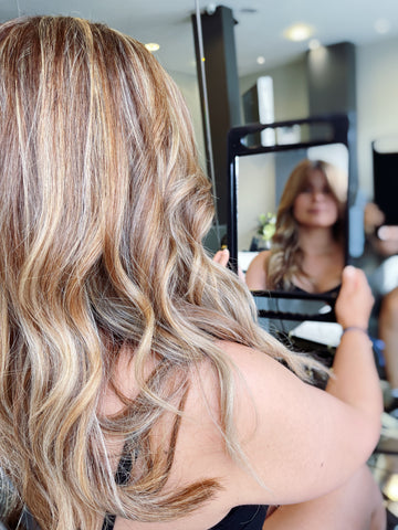Woman looking in mirror at long, beautiful, soft, healthy hair