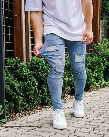 Man stretching blue ripped jeans
