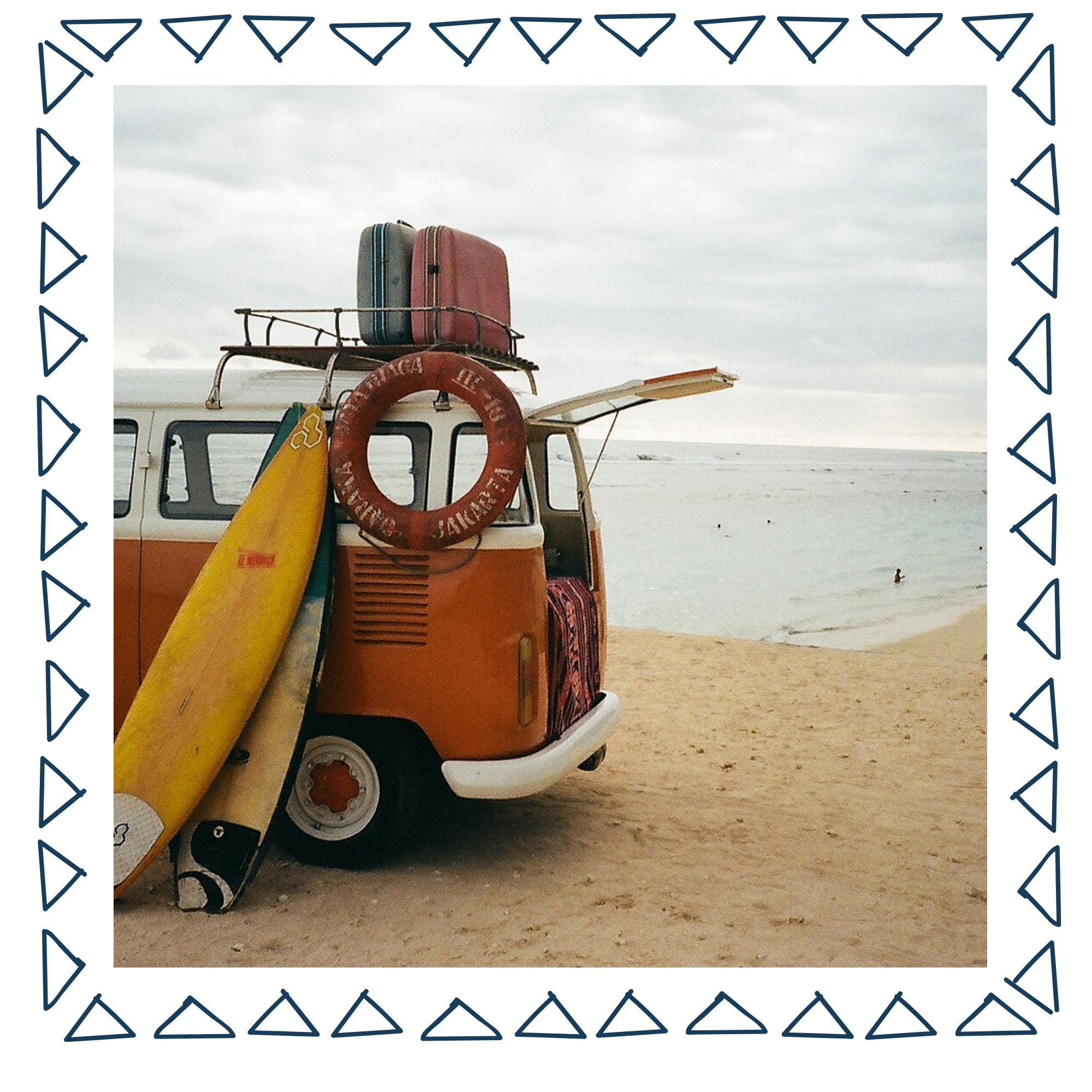 a 60s style VW Bus with surfboards and luggage on the top parked at the beach