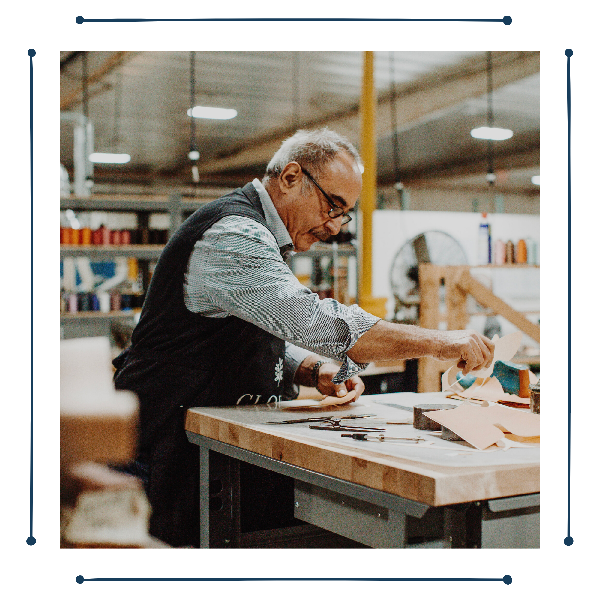 artisan in a Clover and Cobbler apron working at a workbench at the factory