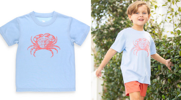 little boy wearing a light blue crab tshirt walking down the street