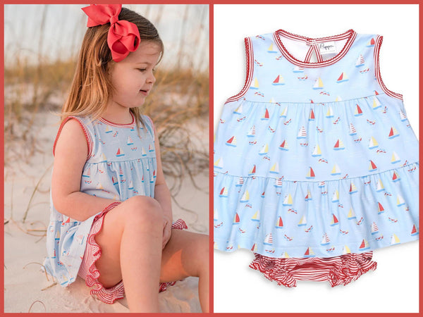 cute little girl with a red bow in her hair on the beach in a summer outfit