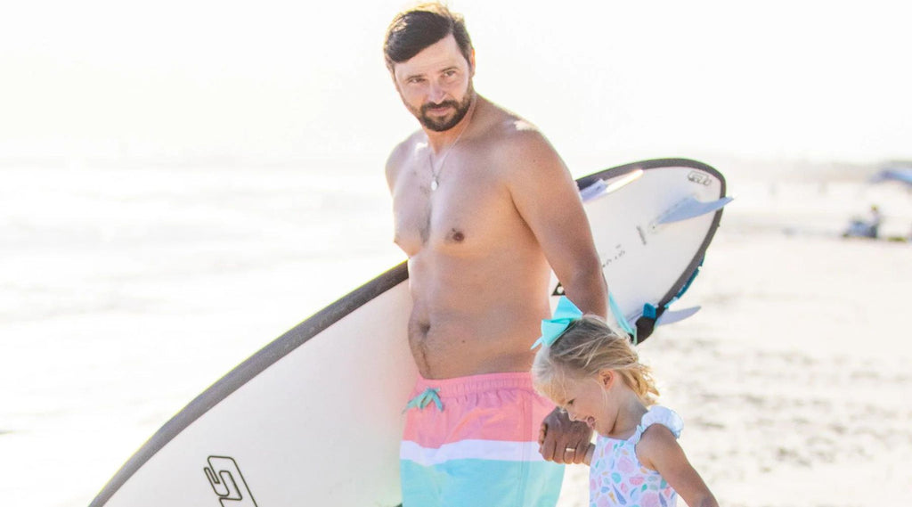 father and daughter at the beach with a surfboard