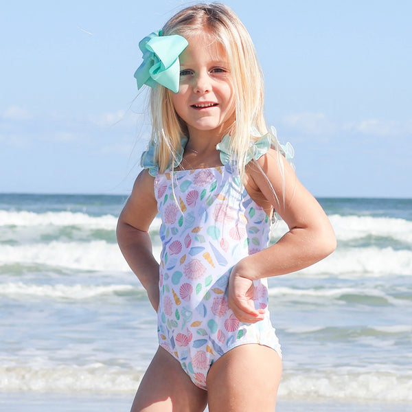 little girl in a one piece bathing suit on the beach