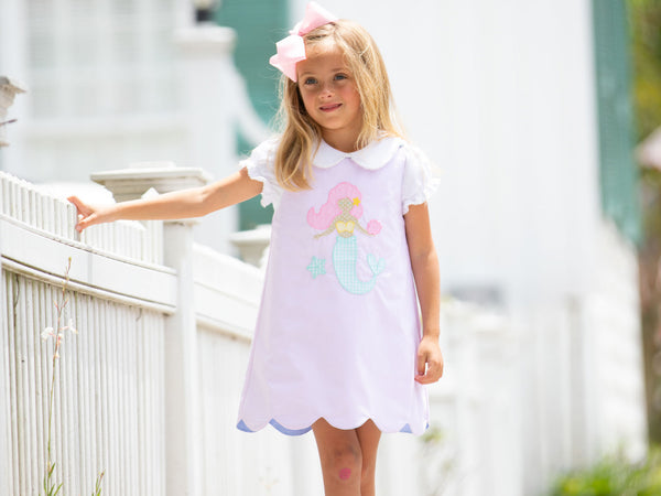 little girl in dress standing by fence