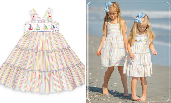 2 little girls on the beach wearing a smocked sailboat dress