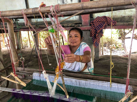 Indian woman took in front of a loom, weaving fabric in Assam