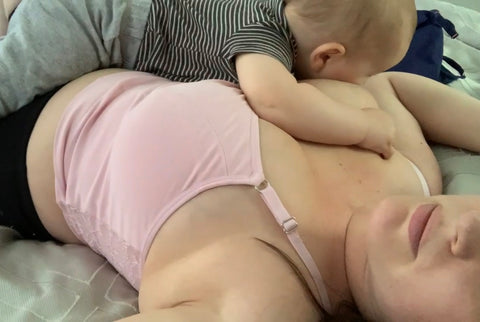 woman laying down while breastfeeding a young baby